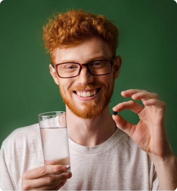 Person holding an astaxanthin supplement and a glass of water